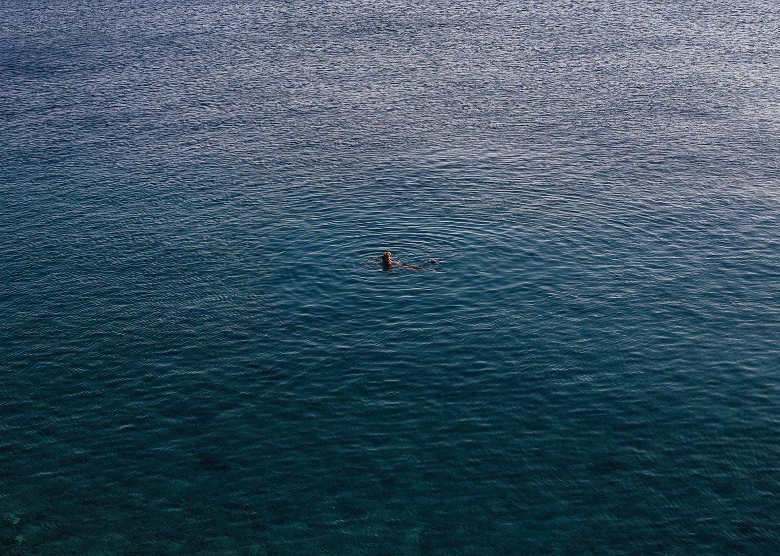 Een zwemmer alleen in rustig zeewater, van bovenaf gefotografeerd